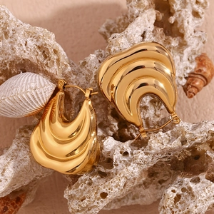 Macro shot of gold hollow boat earrings on reef rock showing 18K gold plated texture