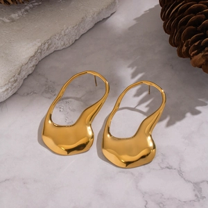 Macro view of golden geometric irregular earrings with liquid metal texture on marble