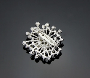 Detail of silver snowflake brooch showing the secure safety pin clasp on the back