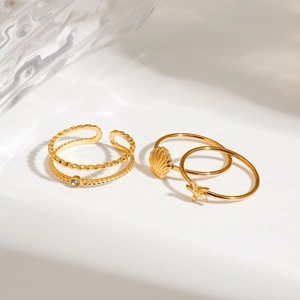 Three-piece gold stainless steel ring set featuring shell, starfish, and wavy crystal designs