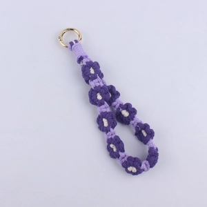 Detail of a handmade woven daisy keychain with purple cotton rope and gold ring clasp