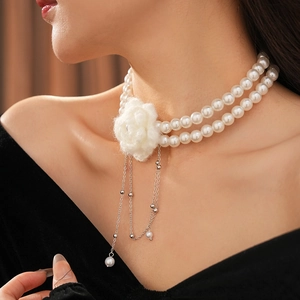 Close-up of double-layer pearl necklace with plush white flower and metal tassels