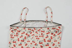 Close-up of cream floral camisole featuring red cherry print and black lace trim edges