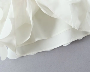 Dettaglio dell'orlo dell'abito bianco con paillettes, chiffon e decori 3D