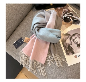 Detail of 100% pure goat wool scarf with gradient ripples and tassels on a grey sofa