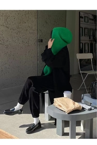 Detail of a chic green hooded scarf shawl worn with a black coat in a casual cafe setting