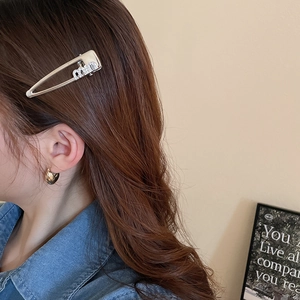 Detail view of silver rhinestone Miu letter pin hairpin worn on side of hair