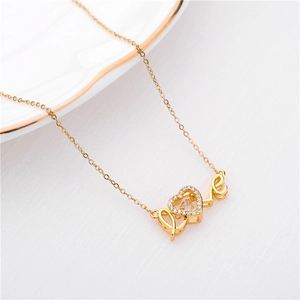 Close-up of golden titanium necklace with LOVE heart pendant on white cloth background