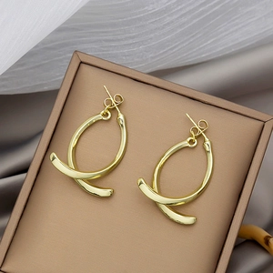 Detailed close-up of golden geometric double-hoop earrings on soft silk fabric texture