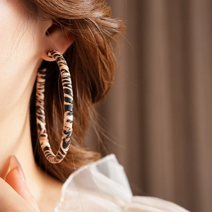 Close-up of leopard print hoop earrings on a model featuring vintage texture details