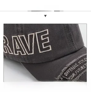 Detail of washed grey baseball cap featuring bold RAVE embroidery and distressed brim edge