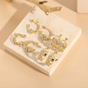 Close-up of gold twist hoop earrings and heart-shaped zircon studs on a stone display