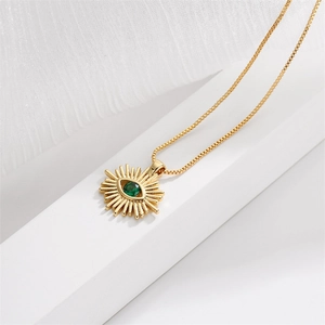 Collier doré avec pendentif œil de démon en zircon vert sur fond en tissu blanc