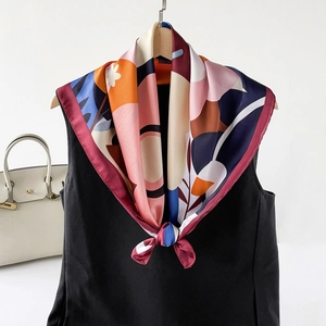 Abstract geometric print square silk scarf draped over a black vest for styling