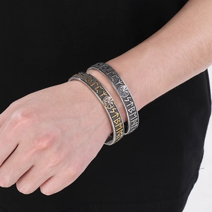 Detail of Viking Rune stainless steel open bracelets in gold and silver on a male wrist