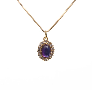 Gouden ketting met paarse ovale edelsteen en zirkonia op witte achtergrond studiofoto