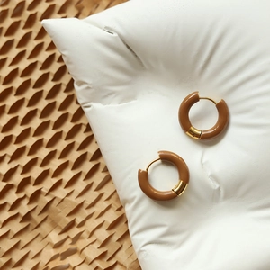 Macro view of brown enamel and 18K gold plated titanium steel hoop earrings