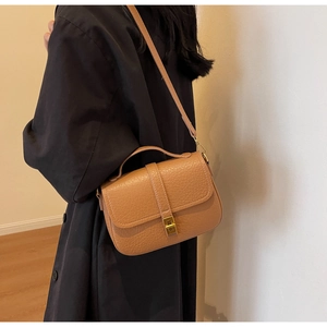 Close-up of brown litchi grain leather bag with a gold rectangular metal clasp
