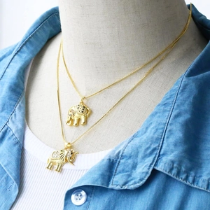 Close-up of dual-layered gold elephant necklaces with micro-set zircons on a model