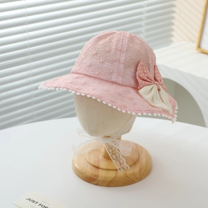 Close-up of pink lace baby sun hat with polka dot bow and pom pom details