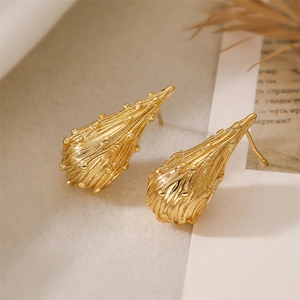 Macro shot of gold teardrop earrings featuring vertical stripes and micro-bead textures