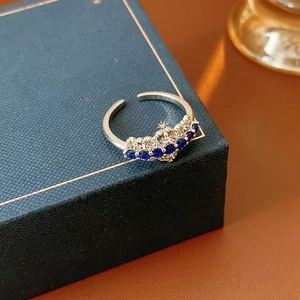 Vue macro d'une bague argentée avec pierre bleu foncé et dentelle de zircon brillant