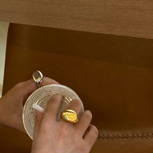 Anillos irregulares de metal líquido en oro y plata usados con una bebida refrescante
