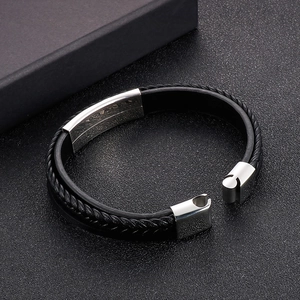 Detail of multi-layer black braided leather bracelet with polished steel ID plate