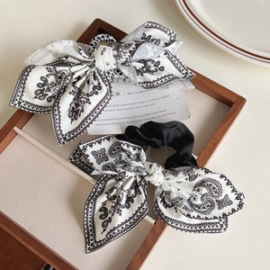 Detail of high-quality fabric bow hair clips with vintage paisley heart patterns in black and white