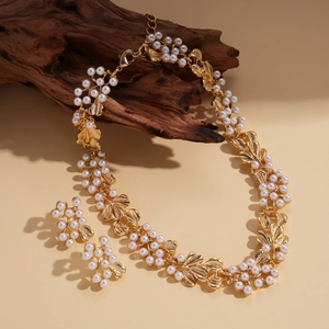 Detailed shot of vintage gold leaf necklace and pearl earrings on rustic wood background