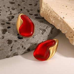 Minimalist red teardrop earrings with gold organic frames on volcanic rock base
