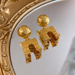 Vintage golden Arc de Triomphe earrings with relief sphere on a mirror background
