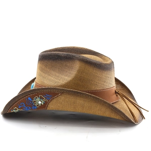 Détail d'un chapeau de cowboy en paille tissée avec broderie florale bleue et gland