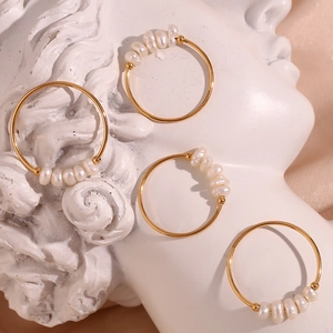 Artistic display of four 18K gold plated rings with small freshwater pearls on a statue