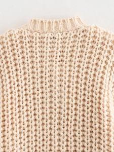 Close-up detail of beige chunky knit cardigan showing neck and shoulder texture