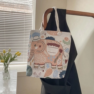 Detail of embroidered canvas tote bag with pink elephant pattern and rope handle