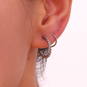 Macro shot of silver twisted hoop earrings and minimalist ring set for double piercing