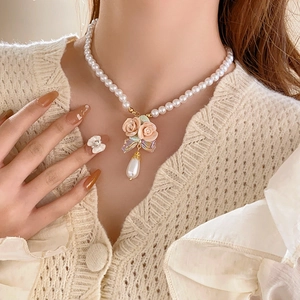 Close-up of elegant French style floral pendant and pearl necklace on woman neck