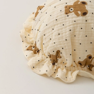 Detail of baby muslin hat featuring brown bear prints and ruffled edge texture