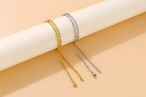 Detail view of gold and silver hammered chain necklaces draped over a cylindrical prop