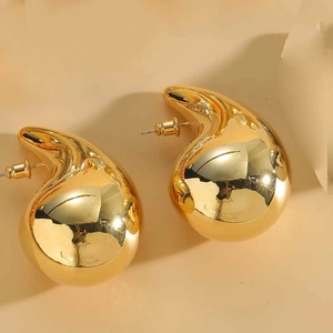 Close-up of polished golden drop earrings with a smooth mirror finish on a warm background