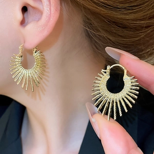 Close-up of golden sunburst irregular earrings showing detailed radial metal texture