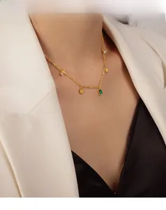 Detailed view of gold necklace with emerald green gemstone and sun-shaped charms on model