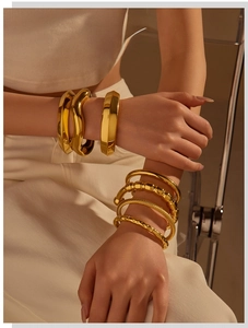 Detail of stacked gold cuff bracelets with wavy, hammered, and rope texture designs