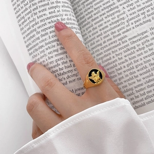 Close-up of a vintage gold ring featuring a black enamel surface with an angel relief