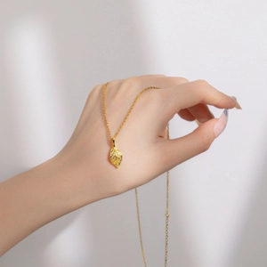 Close-up of a gold leaf pendant necklace with shimmering zircon stones on a fine chain