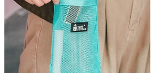 Close-up of green mesh water bottle sleeve featuring a black Time Stroll woven label