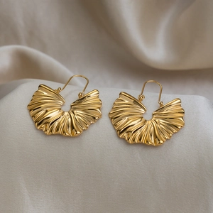 Boucles d'oreilles minimalistes en acier doré en forme d'éventail sur fond de soie beige