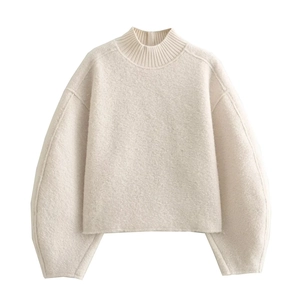 Close-up of cream knit sweater showing high neck design and thick woven fabric texture