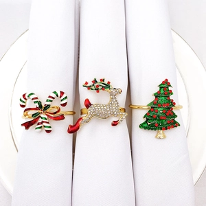 Close-up of metal Christmas napkin rings set with reindeer and tree designs on white plates